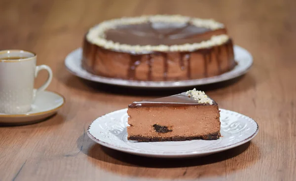 Cheesecake de chocolate com avelãs. Uma fatia de um bolo de queijo de chocolate em um fundo de madeira — Fotografia de Stock