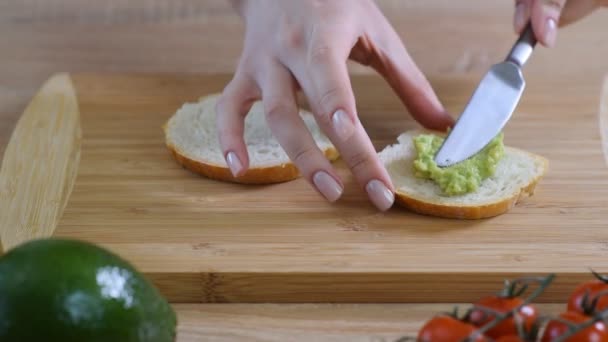 Vrouw verspreiden aardappelpuree avocado op toast — Stockvideo