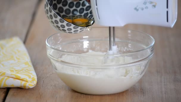Adicionar ovos à massa. Fazendo bolo na cozinha . — Vídeo de Stock