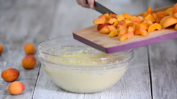 Шеф-повар добавляет абрикосы в тесто. Рука смешивает абрикосы с тестом. Торт с абрикосами . — стоковое видео