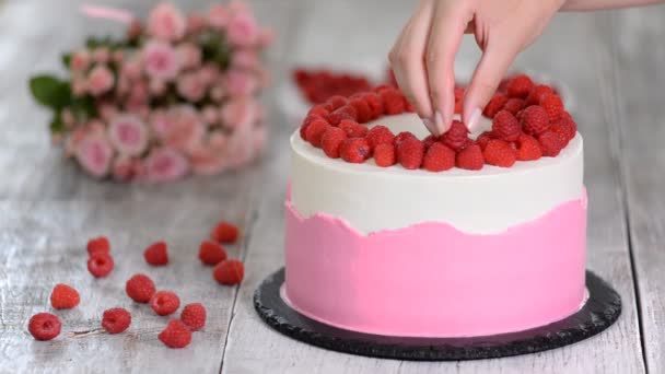Pastry chef in the kitchen decorating a cake with raspberries. — Stock Video
