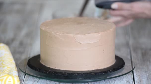 Schokoladenkuchen. Konditor deckt Schokoladenkuchen cremige Sahne. Schokoladenbiskuit vorhanden. Teigtasche mit Sahne. — Stockvideo