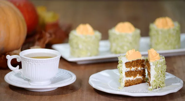 Pumpkin cakes with a cup of tea on wooden background.