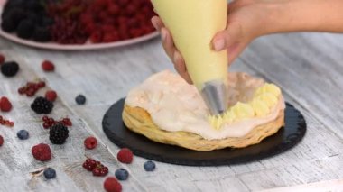 Bayan pasta şefi boru torbası ve dönen kek standı kullanarak ev mutfağında masada duran krem frosting ile pasta süslemek için standı.