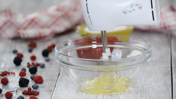 Vrouwelijke handen kloppende eiwitten crème met de mixer in de kom. — Stockvideo