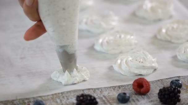 Mani di uno chef che cucina meringa in cucina. Tubo di pasticceria spalmato meringa su una teglia . — Video Stock