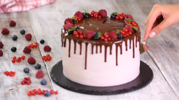 Mooie zelfgemaakte taart met zomer bessen, chocolade glazuur op witte tafel. — Stockvideo