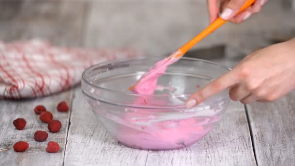 Hand stirring vanilla cream with pink in mixing bowl. — Stock Video