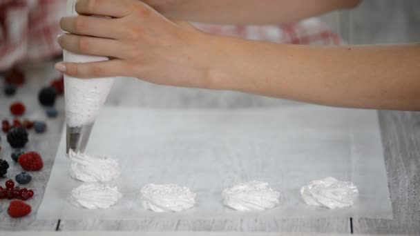 Manos de un chef cocinando merengue en la cocina. Tubo de pastelería extendido merengue en una bandeja para hornear . — Vídeos de Stock