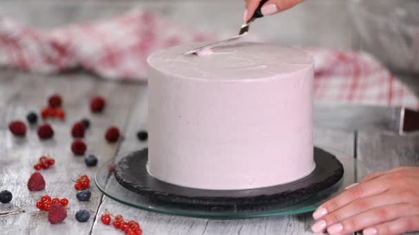 Paso a paso. Mujeres mano extendiendo crema batida en la torta de esponja. Panadero preparación de pastel con crema usando espátula — Vídeos de Stock