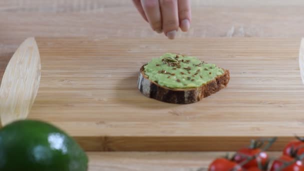 Toast mit Avocado, Leinsamen auf rustikalem Holzgrund. gesundes Frühstück. — Stockvideo