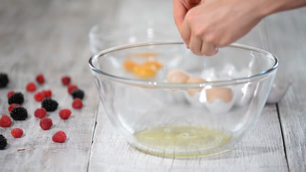 Τα γυναικεία χέρια χωρίζουν το λευκό αυγό από τον κρόκο πάνω από ένα μπολ στην κουζίνα.. — Αρχείο Βίντεο