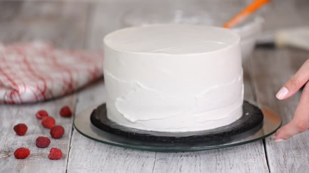 Paso a paso. Mujeres mano extendiendo crema batida en la torta de esponja. Panadero preparación de pastel con crema usando espátula . — Vídeo de stock