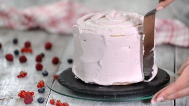 Sünger tabakaları lezzetli kek ve dönen kek standı kullanarak bir krem şanti yapma kadın pasta şef eller.
