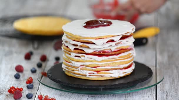 Manos de chef de pastelería femenina haciendo delicioso pastel de capas de esponja, crema batida y mermelada de bayas utilizando soporte de pastel giratorio . — Vídeos de Stock