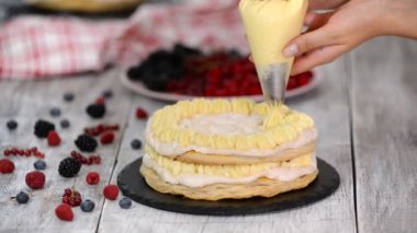 Bayan pasta şefi boru torbası ve dönen kek standı kullanarak ev mutfağında masada duran krem frosting ile pasta süslemek için standı.