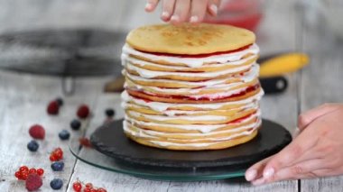 Sünger tabakaları lezzetli kek yapma kadın pasta şef eller, dönen kek standı kullanarak krem şanti ve berry reçel.
