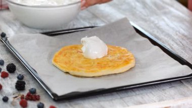 Kadın pişmiş puf böreği üzerine beze koyar. Yaz meyveleri ile katmanlı kek yapma