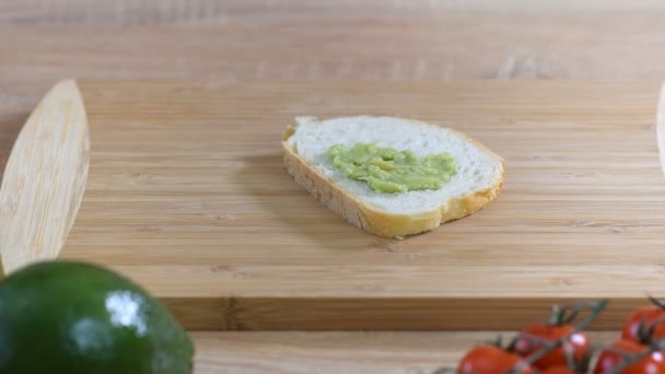 Una mujer esparce puré de aguacate en tostadas. Desayuno saludable — Vídeos de Stock