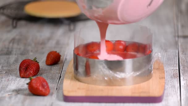 Uma mulher na cozinha faz bolo de mousse de morango. Derramando mousse de morango no anel de confeitaria. Comida doce — Vídeo de Stock