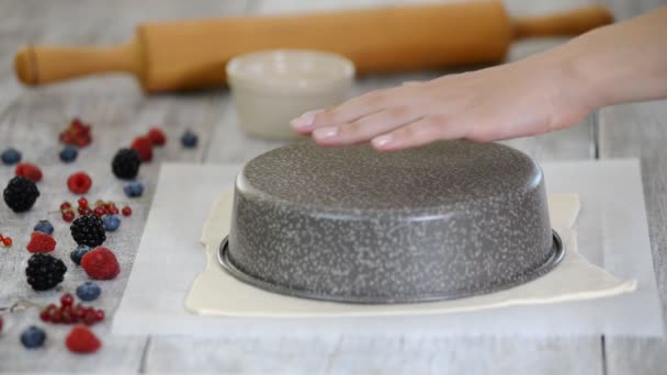 Cocine cortando la masa en círculo para hornear hecho en casa. Mujer cortando masa cruda en el papel pergamino con un cuchillo . — Vídeo de stock