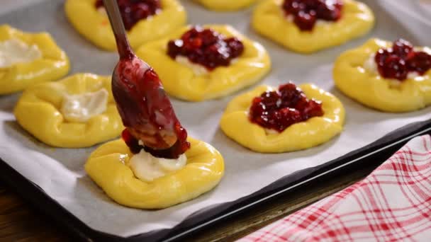 Rohe süße Hefeteig auf einem Backblech, füllen Brötchen mit Kirsche. — Stockvideo