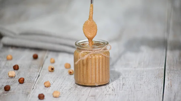 Haselnussbutter im Glas auf einem Holztisch. — Stockfoto