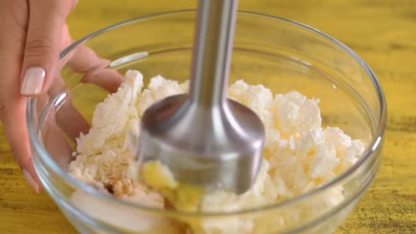 Жінка змішує сир з цукром і яйцем з блендером . — стокове відео