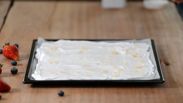 Het concept van koken. Een professionele banketbakker maakt een meringue roll, strooi amandel vlokken op de basis. — Stockvideo