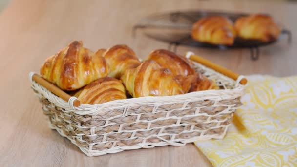 Čerstvé croissanty v proutěném koši na dřevěném stole — Stock video