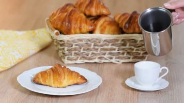 Ahşap arka planda kruvasanlı taze kahve. Bir bardağa espresso dökmek