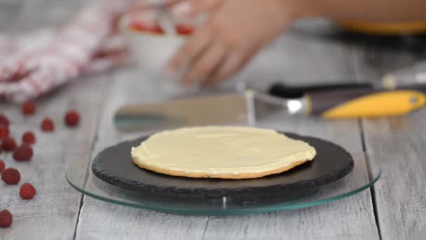 En tjej som gör en tårta i ett bageri. Baker kramar grädde på en kaka blank. Vit kaka på ett träbord. — Stockvideo