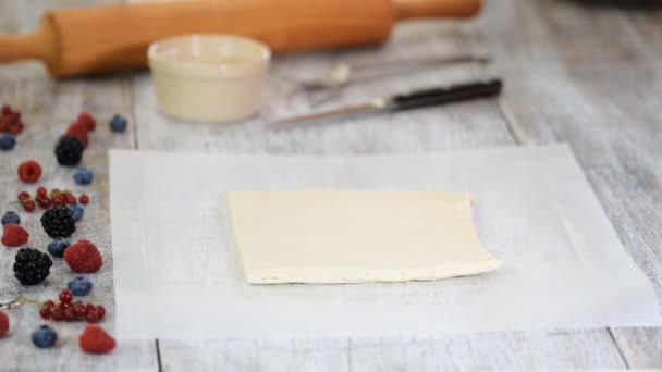 Koch rollt Blätterteig auf Pergamentpapier. Millefeuille mit Beeren machen — Stockvideo