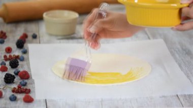 Kek tabakasına yumurta bulaştırmak. Pişirme tatlı hamur işleri.