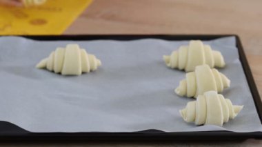 Kadın aşçı mutfakta bir pişirme tepsisinde kruvasan düzenlenmesi. Fırında uzak yiyeceklerin pişirimi.