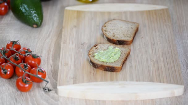Sandwich bread and mashed avocado on table. — Stock Video