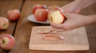 Yemek elma bir ahşap tahta üzerinde peeling eller.