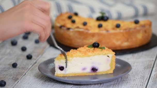 Trancher le gâteau au fromage avec les bleuets sur une assiette. Femme manger gâteau au fromage aux myrtilles . — Video