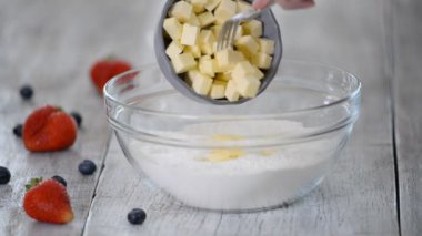 Pişirmek için malzemelerin hazırlanması. Kadın elleri kaseye un ile tereyağı ekler..