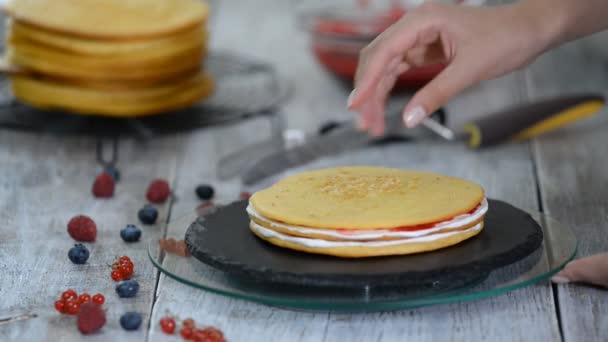 Кондитер намазывает крем на слои торта. Процесс приготовления торта с начинкой из ягод . — стоковое видео