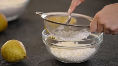 Pasta şefi kadın peyniri süzgeçten siliyor..