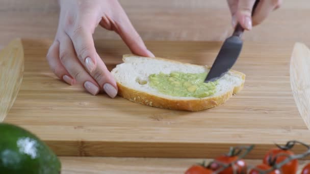 Spridning mosade avokado på bröd. Göra en hälsosam frukost. — Stockvideo