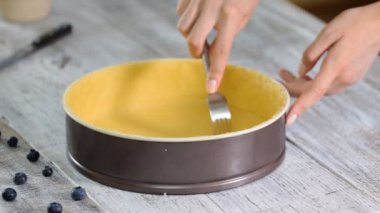 Kadın, çiğ hamur işi kutusunu çatalla delip geçti. Tarif konsepti.