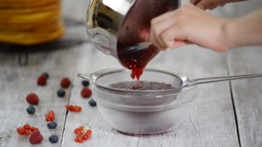 Mutfakta bir kadın ahududu ve frenk üzümü reçeli yapıyor..