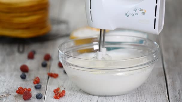 Γυναίκα σεφ ζαχαροπλαστικής χτυπώντας κρέμα με μίξερ χειρός. Προσθήκη ζάχαρης σε σκόνη στην κρέμα γάλακτος. — Αρχείο Βίντεο