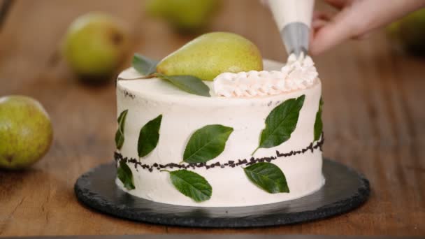 Decorar un pastel con crema usando una bolsa de tuberías. Mujer pastelera hace pastel de chocolate con pera . — Vídeos de Stock