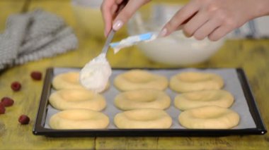 Kadın mutfakta tatlı açık çörekler pişiriyor süzme peynir, ahududu ve shtreyzelem ile. Ev yapımı hamur işi, pişmiş çörekler vatrushka.
