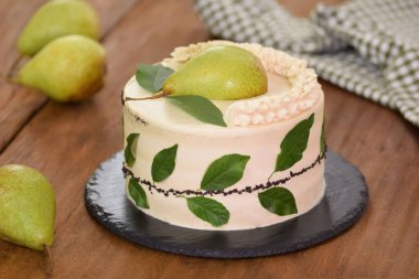 Cream cake with decorated with fresh pear and green leaves.