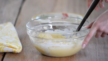 Genç bir kadın mutfakta para kazanıyor. Hamura un ekle.