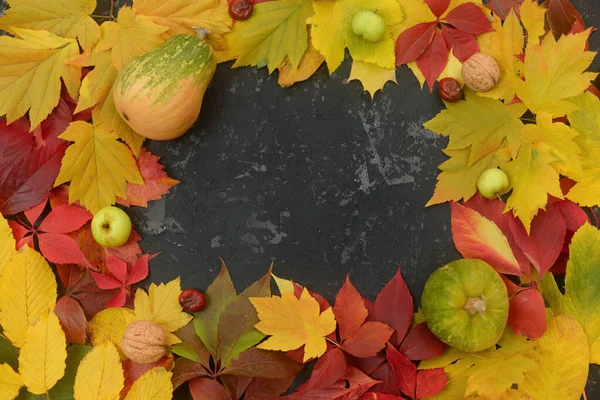 Calabaza, manzanas y nueces sobre una mesa negra con hojas amarillas otoñales . —  Fotos de Stock